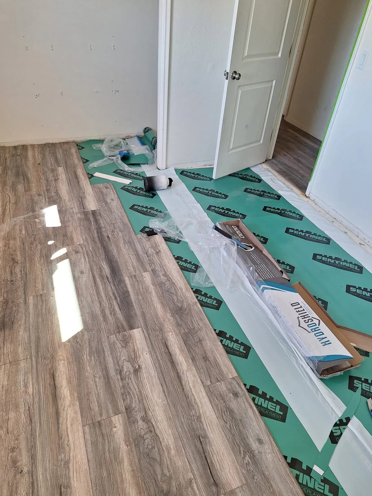 Plank flooring installation progressing across the bedroom